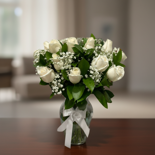 Ramo de rosas blancas en jarrón de cristal Ramo de rosas blancas con paniculata y hojas verdes en jarrón de cristal con lazo blanco sobre mesa de madera