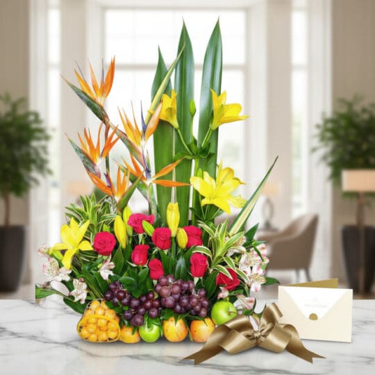 Arreglo floral Akebia con aves del paraíso, rosas rojas, lirios amarillos y frutas tropicales sobre mármol, listo para regalo