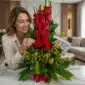 Mujer elegante sonriendo y admirando un arreglo floral de rosas rojas y flores amarillas, con un lazo rojo y una tarjeta, en