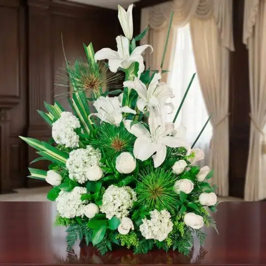 Arreglo fĂșnebre AdiĂłs Para Siempre con lirios, hortensias y rosas blancas, en una sala de velaciĂłn premium con luz natural y