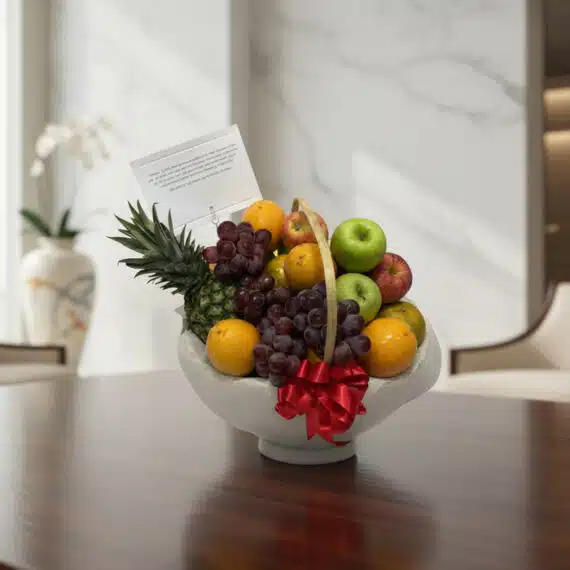 Canasta de Frutas Gourmet: El Regalo Saludable y Elegante Perfecto Canasta de frutas gourmet con piña, uvas, manzanas y naranjas, sobre una mesa de madera pulida en un entorno elegante.