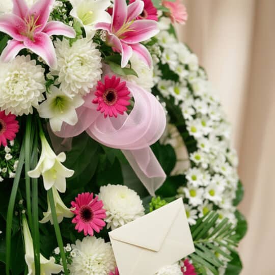 Detalle de la Corona Fúnebre Solemne "Homenaje a Mathias" con lirios blancos y rosas, crisantemos y gerberas, con cinta satin