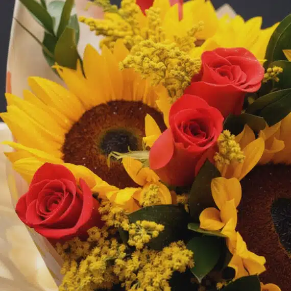 Primer plano extremo de un Ramillete o Bouquet Primavera con girasoles grandes, rosas rojas frescas y flores amarillas comple