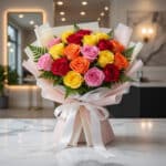 Ramillete o bouquet de 18 rosas multicolor (rojas, amarillas, naranjas, rosas) con empaque coreano elegante sobre mesa de már